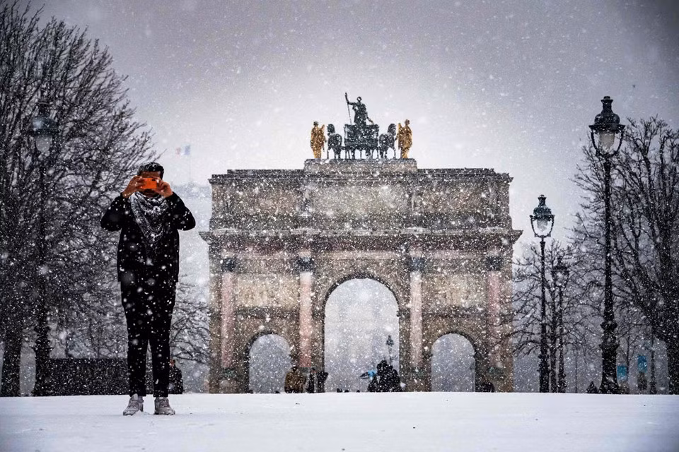 Một người đàn ông chụp ảnh trong khu vườn Tuileries khi tuyết rơi ở Paris. Các công trình nổi tiếng của Pháp đều bị bao phủ bởi tuyết trắng. Thời tiết ảm đạm với mây mù và gió lạnh cũng đang hoành hành ở một phần Tây Âu.