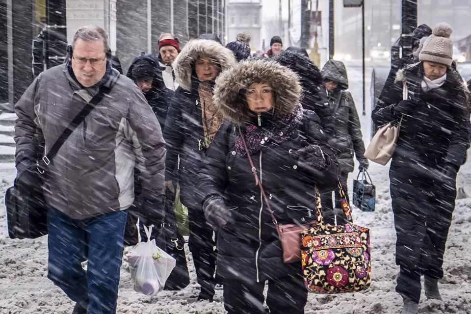 Người đi làm buổi sáng 28/1 dưới tuyết rơi dày tại đường Wacker Drive ở thành phố Chicago, nơi nhiệt độ tối 30/1 được dự báo thấp nhất -33 độ C (-46 độ C nếu tính tác động của gió - lạnh hơn một số nơi ở Nam Cực, Bắc Cực hoặc Alaska). Giới chức thành phố cảnh báo không nên bước ra ngoài trời dù chỉ vài phút. Nhưng Tony Neeler đã đứng ở một góc đường trong vài giờ. “Tôi lạnh và sợ hãi”, ông Neeley nói. Đi đôi giày đã ướt và tay nắm chặt gói làm ấm tay, ông đang cố xin đủ 45 đô-la từ những người đi làm để qua đêm trong một nhà nghỉ. Ảnh: AP.