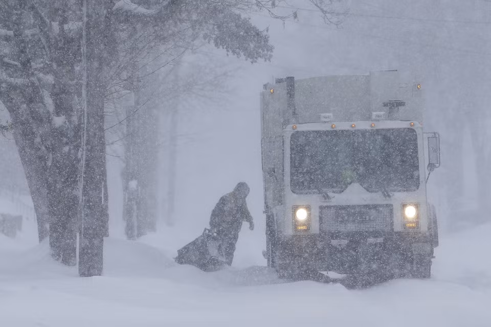 Một công nhân vẫn thu gom rác giữa trận bão tuyết ngày 28/1 ở bang Wisconsin. Bưu điện Mỹ phải ngừng gửi thư ở vùng Trung Tây vì giá rét. Các xe chở bia cũng sẽ ngừng vận chuyển vì sợ bia sẽ đóng băng trong xe. Ảnh: AP.