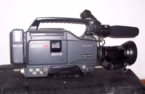 JVC và Sony cùng ra mắt những chiếc máy quay phim cầm tay đầu tiên tại triễn lãm CES năm 1981 và được thương mại hóa lần đầu tiên vào năm 1983. Các máy quay đầu tiên có kích thước khá lớn, ghi hình và lưu trực tiếp lên băng VHS hoach băng cassettes Betamax. Máy quay phim kỹ thuật số đầu tiên được Sony giới thiệu vào năm 1995. So với những máy quay ngày nay, rõ ràng những sản phẩm này đã lạc hậu nhưng thực sự là một bước tiến lớn tại thời điểm ra mắt.