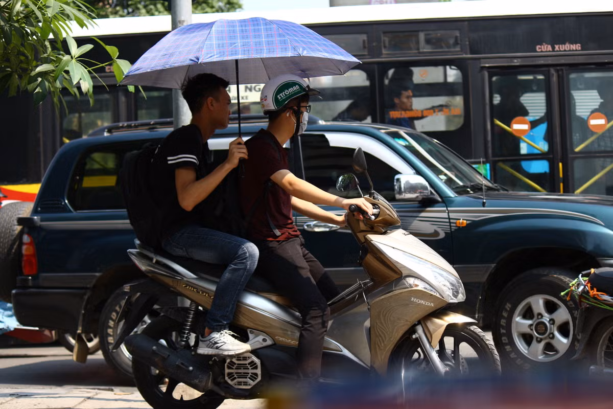 Những người quên mang áo dài tay thậm chí phải dùng cả ô để chống nắng nóng. Mặc dù, việc đi xe máy dùng ô là hết sức nguy hiểm.