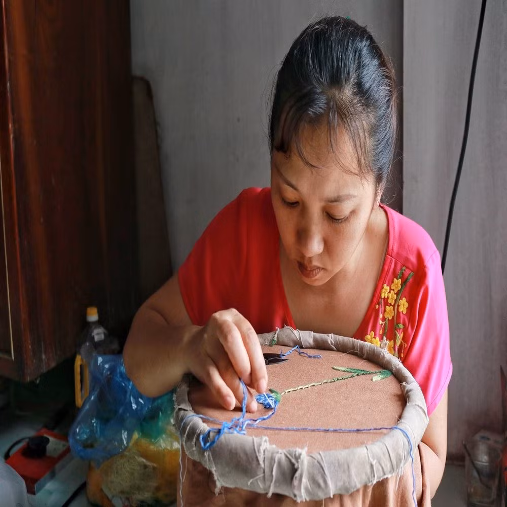 Chị Mai Thị Hải đang thêu các họa tiết trên áo dài giúp cho sản phẩm bắt mắt hơn. Chị Hải chia sẻ: “Công việc này người nào không kiên trì sẽ rất dễ bỏ việc”