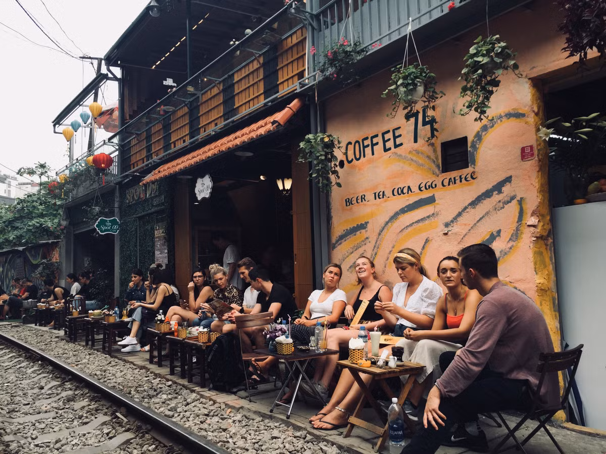 Du khách nước ngoài uống cà phê chờ tàu qua để trải nghiệm cảm giác mạnh.