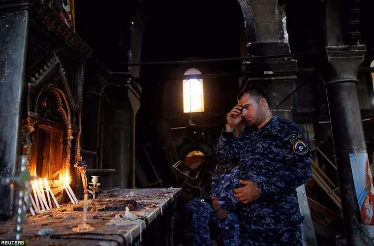 Một cảnh sát Iraq theo đạo Cơ đốc giáo đang làm lễ trong nhà thờ.