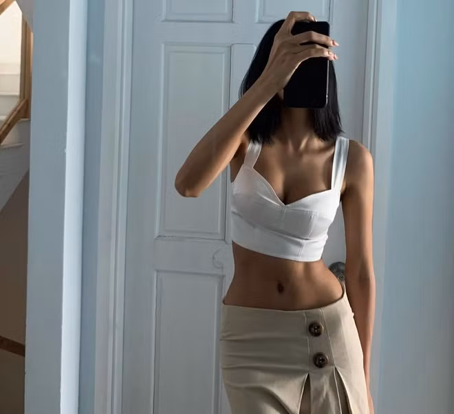 Chuộng gu thời trang hở eo thon, Hoàng Thuỳ diện mẫu crop top gam trắng xẻ sâu phối cùng chân váy bó sát đầy cá tính và gợi cảm.