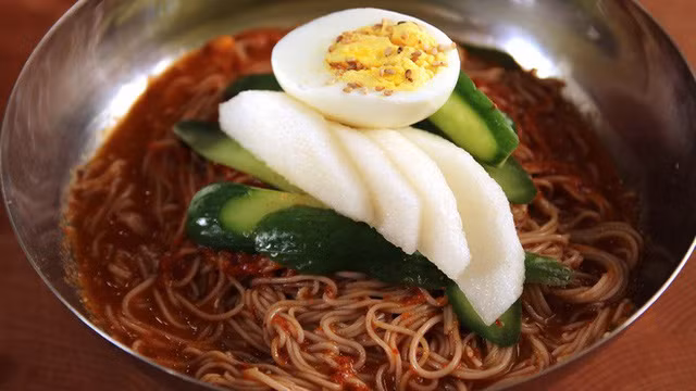  Mì lạnh Hàn Quốc được xem là món ăn yêu thích của cả người Hàn Quốc và Triều Tiên. Không chỉ sợi mì dai ngon mà món ăn còn có sự góp mặt của những nguyên liệu thanh mát như: giá đỗ, dưa chuột, trứng luộc, của cải, lê…