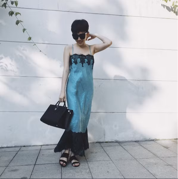Cô diện chiếc váy ngủ màu xanh ngọc với đường viền ren tinh tế ở chân váy và ngực kết hợp cùng đôi sandals bệt quay ngang và túi xách to bản.