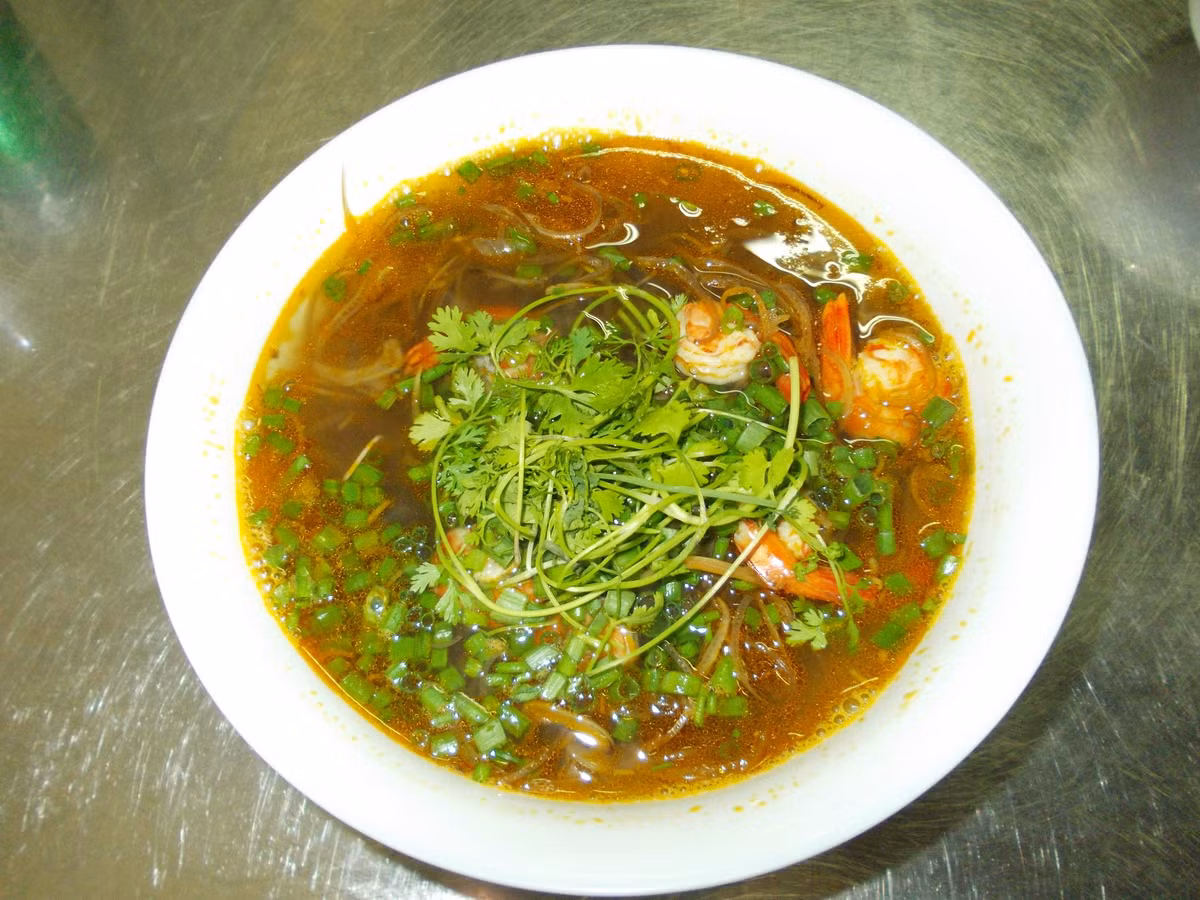 Cho nước đầu tôm vào nồi, lọc mẻ vào đun sôi. Thả cà chua đã thái vào nồi trước, rồi cho tôm vào, nêm nếm gia vị vừa ăn. Khi nước sôi lại, cho tiếp hoa chuối đã để ráo vào. Để nồi canh sôi lại thêm khoảng 5 phút (trong thời gian đó nhớ đảo hoa chuối trong nồi cho chín đều), cho hành và ngổ đã cắt khúc vào, tắt bếp.