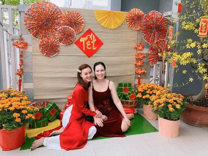 Ninh Dương Lan Ngọc chọn áo dài đỏ có thiết kế cổ trụ truyền thống, khoe nụ cười rạng rỡ bên mẹ trong ngày đầu năm mới.