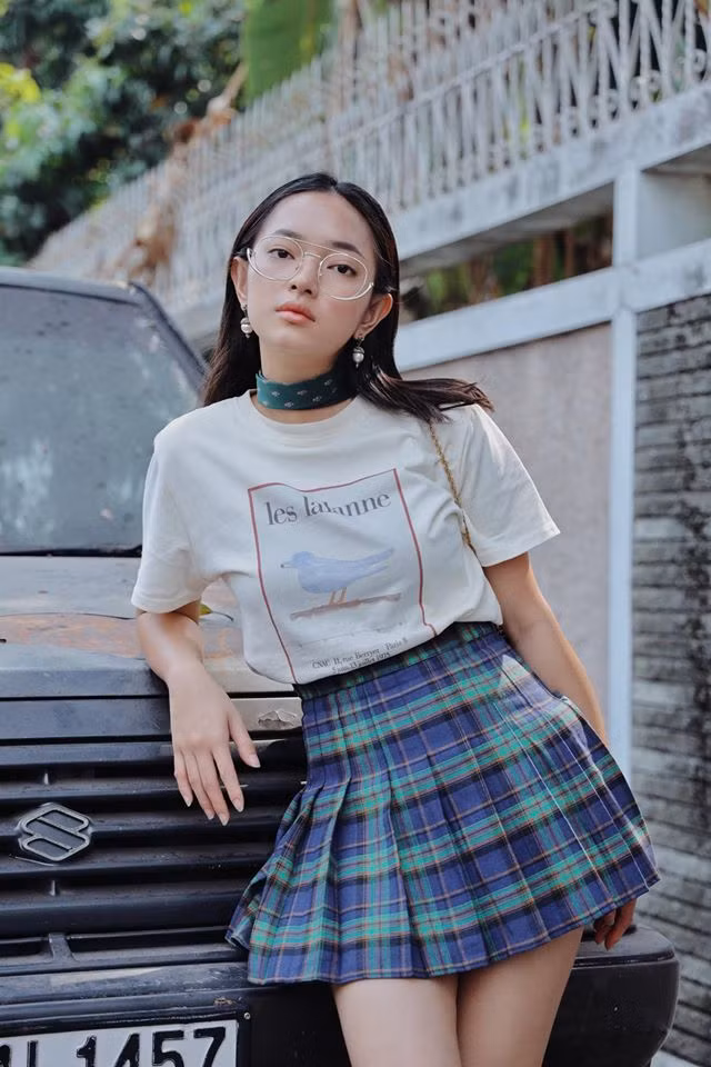 Lúc thì Châu Bùi lại trẻ trung và nữ tính khi phối với áo phông với chân váy kẻ karo theo phong cách nữ sinh. Ảnh: FB. Video "Minh Hằng chia sẻ về phong cách thời trang". Nguồn: VTC.