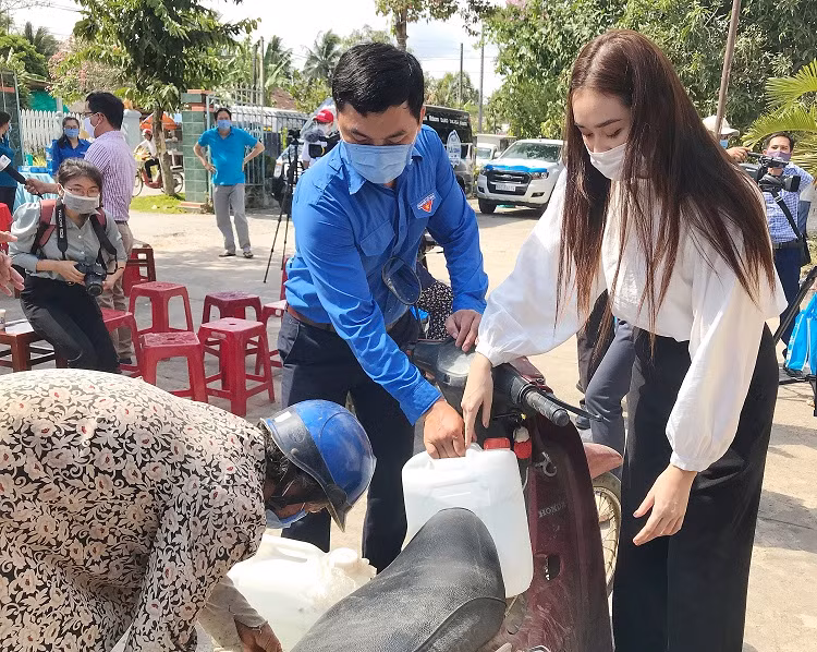 Cô nàng còn tận tay rửa bình và lấy nước giúp người dân.