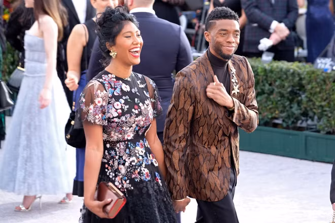 Theo Oprah Magazine, Boseman dẫn bạn gái đến bữa tiệc sau buổi quảng bá phim Black Panther (2018), sự kiện công chiếu phim 21 Bridges. Sau đó, họ tiếp tục được chú ý khi cùng đi xem trận đấu bóng rổ NBA All-star. Trong chuyến đi, diễn viên Michael B. Jordan cũng có mặt. Nhiều lần xuất hiện cùng nhau nhưng truyền thông vẫn không biết lý do anh chưa vội công bố chuyện tình cảm. Ảnh: Splash News.