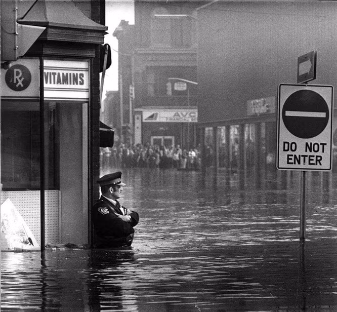 Sĩ quan cảnh sát John Shuttleworth vẫn kiên trì làm nhiệm vụ trong dòng nước lũ ở Cambridge, Ontario, 1974.