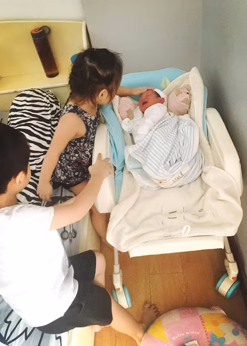 Bé Mio biểu cảm đáng yêu khi được chị gái Cherry cưng nựng. Khi chào đời, nhóc tì thứ 4 của nam đạo diễn phim “Lật mặt” nặng 3kg.