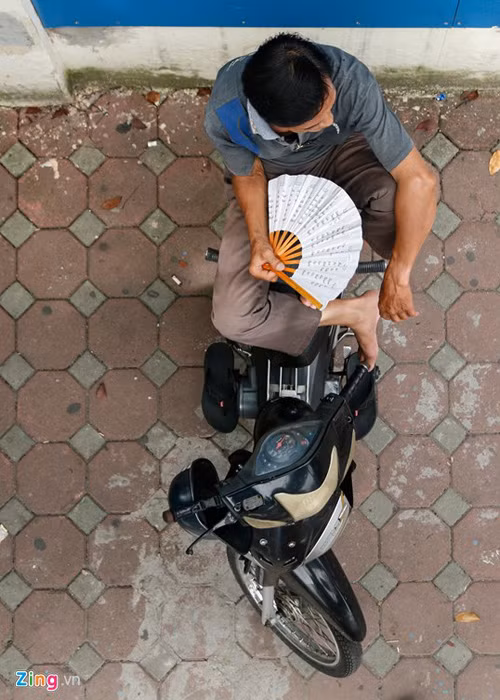 Nỗi lo lắng dường như gây nên sự nóng bức. Mặc dù trời không nắng nhưng người đàn ông này vẫn phải quạt tay. 