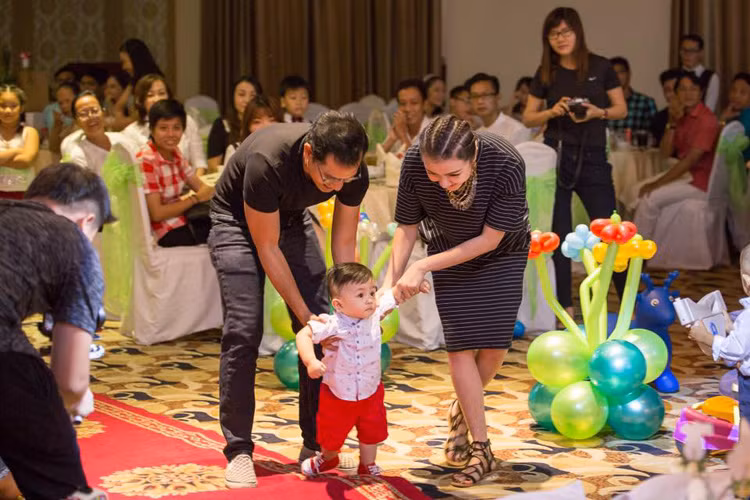 Vợ chồng Huỳnh Đông - Ái Châu ân cần dìu cậu con trai nhỏ bước lên sân khấu chính để bắt đầu tiệc thôi nôi. 