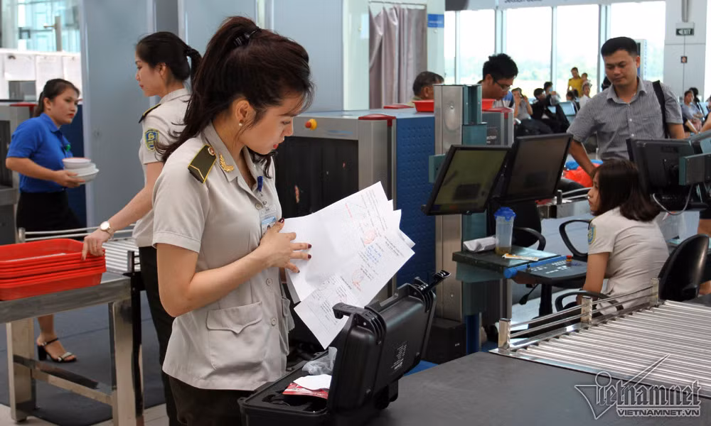 Nhân viên an ninh Nguyễn Thị Bích Ngọc kiểm tra giấy tờ liên quan đến một chiếc máy lạ mắt.