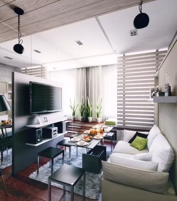 Khoảng không gian chính của căn hộ được chia thành hai khu vực nối tiếp nhau. Một phần diện tích sử dụng để bố trí góc tiếp khách đẹp thanh lịch với màu trung tính. Không gian sinh hoạt chung với ghế sofa không tựa để tiết kiệm tối đa diện tích. Thêm bàn trà và vách ngăn được sử dụng để bố trí ti vi, loa âm thanh.