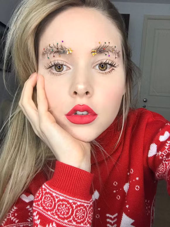 Gần đến ngày Noel, một blogger chuyên về làm đẹp người Canada đã gây chú ý với kiểu trang điểm lông mày hình cây thông. Để tạo được kiểu lông mày độc đáo này, nữ blogger đã chải và tạo hình, rồi khéo léo gắn những hạt nhiều màu sắc lên.