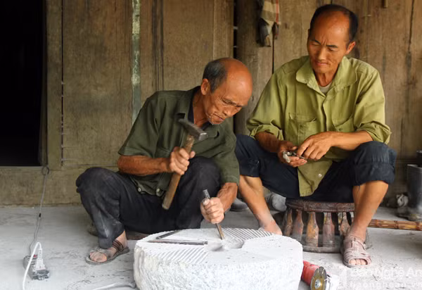 Đám cưới cụ Vừ được tổ chức hai năm trước, với 30 mâm cỗ cùng hơn 300 khách tới dự.Trong đó chủ yếu là con cháu của cụ. Trong ảnh, cụ Vừ cùng người con rể thứ 9 đục cối đá để xay lúa. Ảnh: Tiến Hùng