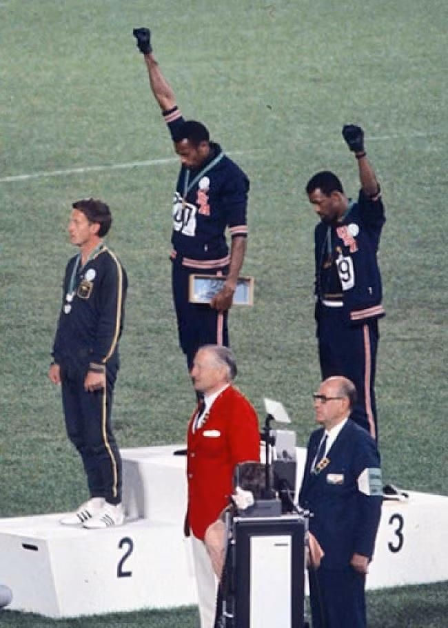  24. Lời chào sức mạnh người da đen tại Olympic 1968 Đây là một hình thức biểu tình chính trị do các vận động viên người Mỹ gốc Phi Tommie Smith và John Carlos tiến hành trong buổi lễ trao huy chương tại Thế vận hội mùa hè 1968 tại Sân vận động Olympic ở thành phố Mexico. Sau chặng đường chạy dài 200 mét, hai vận động viên da đen người Mỹ đã bước lên bục vinh quang. Khi quốc ca Hoa Kỳ, bài “Lá cờ lấp lánh ánh sao” vang lên, cả hai cùng quay mặt về phía quốc kỳ, đồng thời giơ lên trời nắm tay đeo găng đen để ủng hộ phong trào nhân quyền cho những người Mỹ gốc Phi. Thông điệp khá rõ ràng: trước khi chúng tôi chào mừng nước Mỹ, Mỹ phải bình đẳng với người da đen. Các vận động viên giữ nắm tay của họ cho đến khi bài hát kết thúc. 