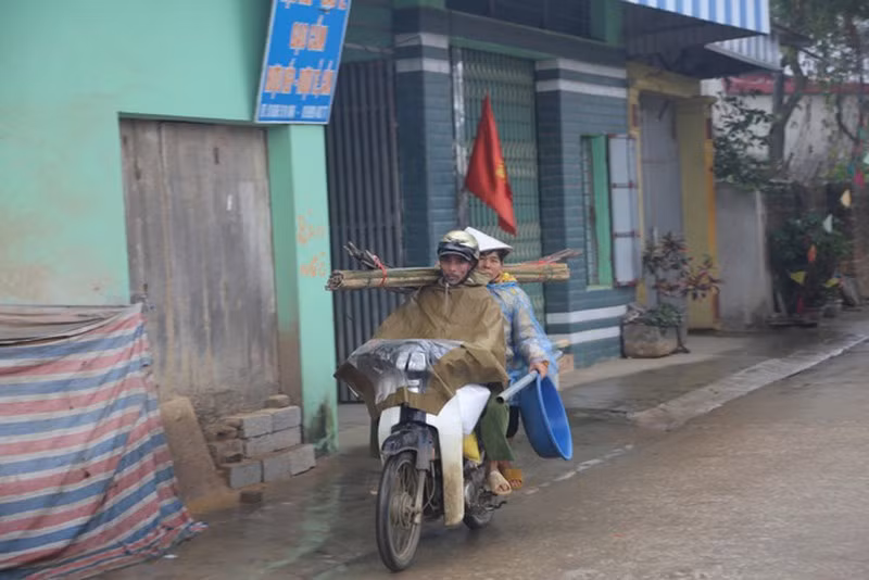 Hai bác nông dân với lỉnh kỉnh đồ đạc chuẩn bị đi làm đồng.