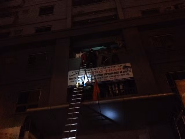 Lực lượng chức năng đang giải cứu người mắc kẹt từ ban công bằng thang gấp cơ động.