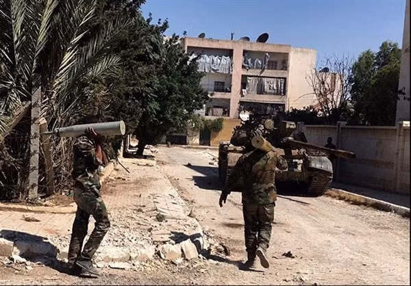 Hai binh sĩ Syria đang vác những quả đạn pháo 100mm nạp cho chiếc xe tăng T-55.