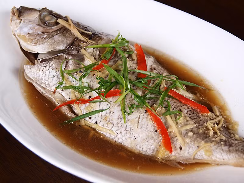 Với món cá hấp, nên đặt miếng mỡ gà lên mình cá. Thịt cá sẽ béo ngậy và thơm ngon hơn. Ảnh: Ang Sarap.