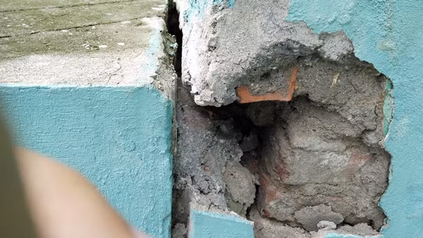 Nhiều mảng tường bị vỡ tung lộ nguyên gạch bên trong.