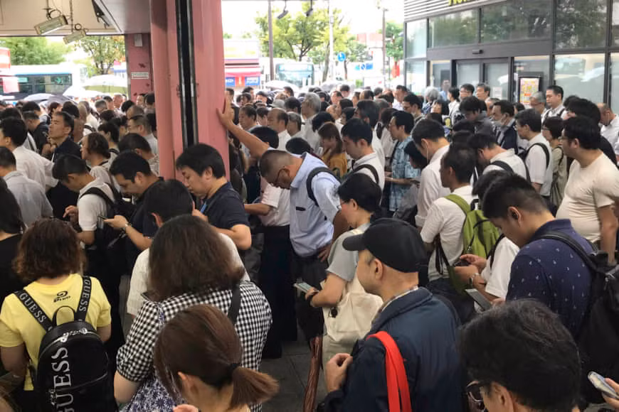 Nhiều hành khách đứng chờ bên ngoài một nhà ga ở Yokohama sau khi dịch vụ đường sắt tạm ngừng hoạt động vì bão Faxai hôm 9/9. Ảnh: AP.