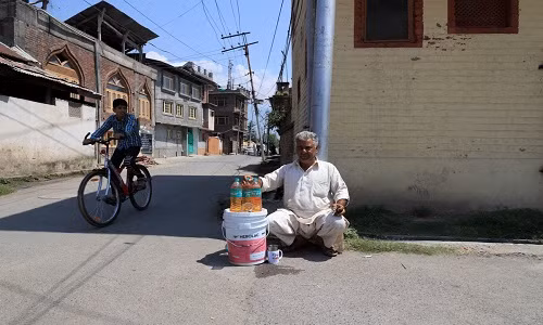 Ông Muhammad Ayoub ngồi bán xăng bên ngoài nhà ở Rainawari. "Tôi từng có nguồn thu nhập ổn định với công việc lái xe lam. Nhưng giờ tôi không còn lựa chọn nào khác để kiếm tiền nuôi gia đình", ông Ayoub chia sẻ.