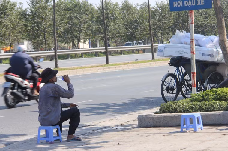 Người đàn ông chạy xe xích lô không chịu nỗi nắng nóng phải dừng chân nghỉ ngơi, tiếp nước trên đại lộ Mai Chí Thọ, quận 2.