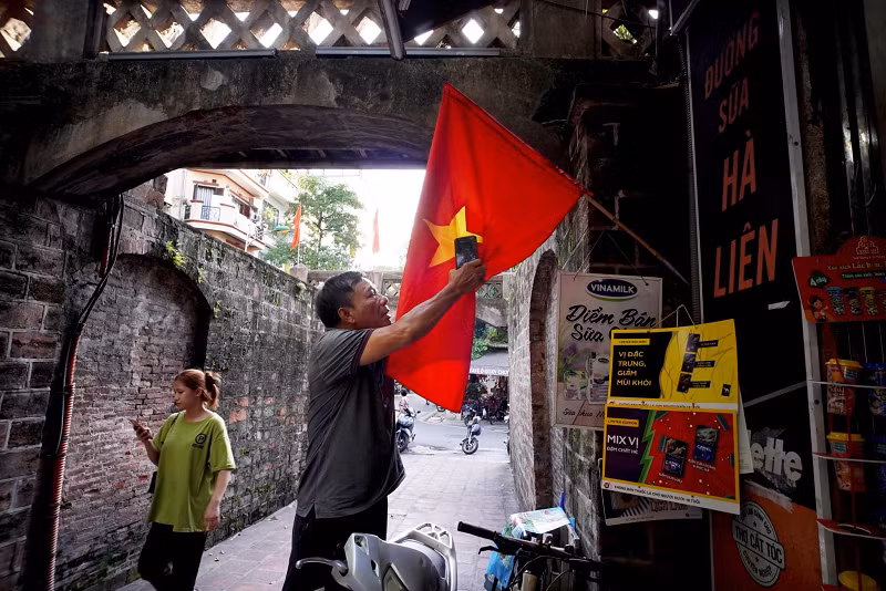 Ông Văn Thành Nhân (trú tại 16B phố Ô Quan Chưởng, Hà Nội) đang chỉnh lại lá cờ bị gió cuộn lại.