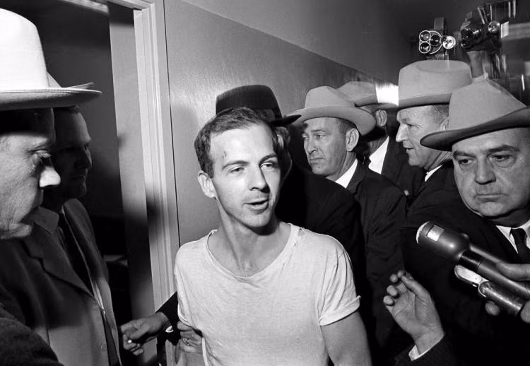 Hai ngày sau khi gây ra vụ ám sát người đứng đầu nước Mỹ, nghi phạm Oswald (áo trắng) bị Jack Ruby bắn chết ngay tại đồn cảnh sát Dallas.