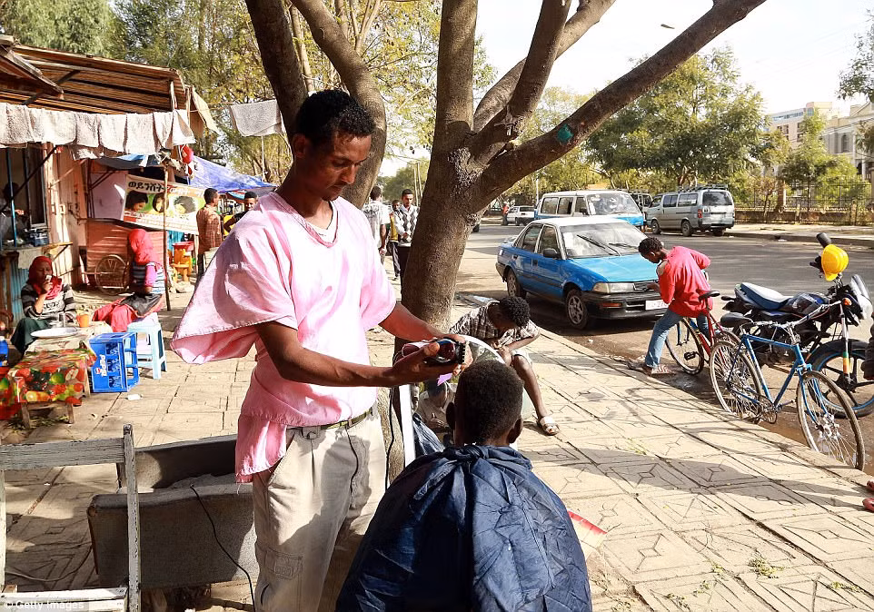 Một người thợ cạo vỉa hè Ethiopia. Trong ảnh là Tariku Alemu kiếm được khoảng 7 bảng mỗi ngày bằng việc cắt tóc cho khách hàng ở đường phố Addis Ababa.