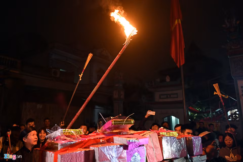 Một bô lão trong làng xin lửa từ trên điện thờ. Sau khi mang vàng hương đổ ra giữa sân, cụ châm lửa Thánh từ cây sào lớn để hoá.