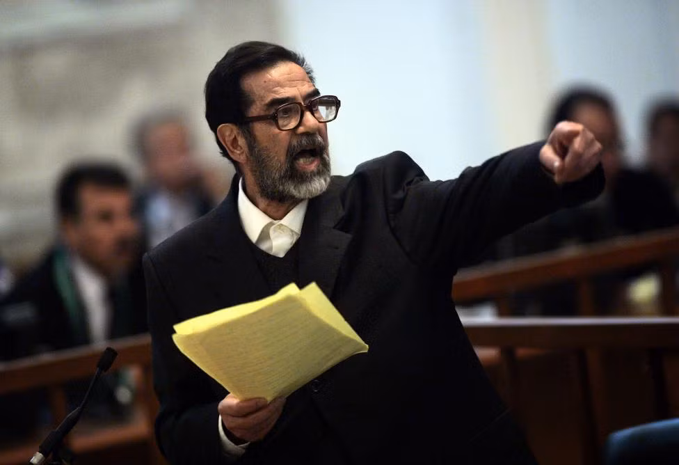 Cựu Tổng thống Iraq Saddam Hussein tranh luận với các công tố viên trong phiên xét xử ông ở khu vực giới tuyến xanh ở Thủ đô Baghdad ngày 5/4/2006. Tháng 12 năm đó, ông đã bị treo cổ sau phán quyết của tòa án.