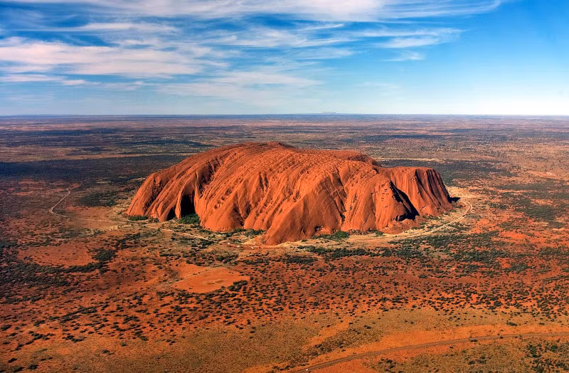 Chiều cao của núi Uluru là khoảng 348m, dài 3 km và chu vi chân núi khoảng 8,5 km. Nhìn từ xa, đây là một khối đá khổng lồ và bóng nhẵn. Điều thú vị và kỳ lạ là núi Uluru có khả năng tự biến đổi màu sắc tùy theo thời tiết, khoảng thời gian trong ngày. Ảnh: Corey Leopold CCL.