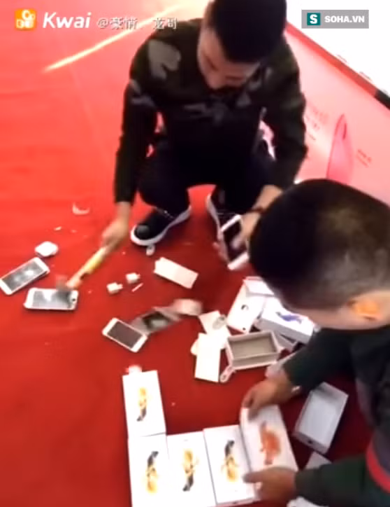 Những chiếc iPhone vỡ nát theo từng nhát búa dưới sàn nhà. Ảnh: Kwai.