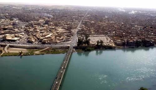 Thành phố ban đầu tọa lạc ở bờ tây của sông Tigris, đối diện với thành phố cổ Assyria Nineveh ở bờ đông, nhưng khu vực đô thị hiện đã phát triển, bao gồm các khu vực khá lớn trên cả hai bờ sông, với năm cây cầu nối hai bờ. Ảnh: Wiki.
