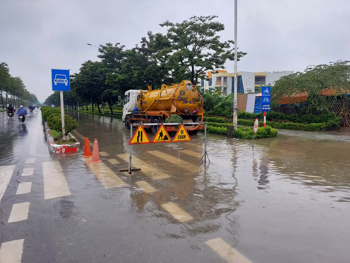 Làn xe máy, xe đạp của đường Trịnh Văn Bô bị ngập sâu, các phương tiện không thể di chuyển. Để bảo đảm an toàn, một chiếc xe bồn được bố trí chặn đường, không cho các phương tiện qua lại để chờ nước rút.