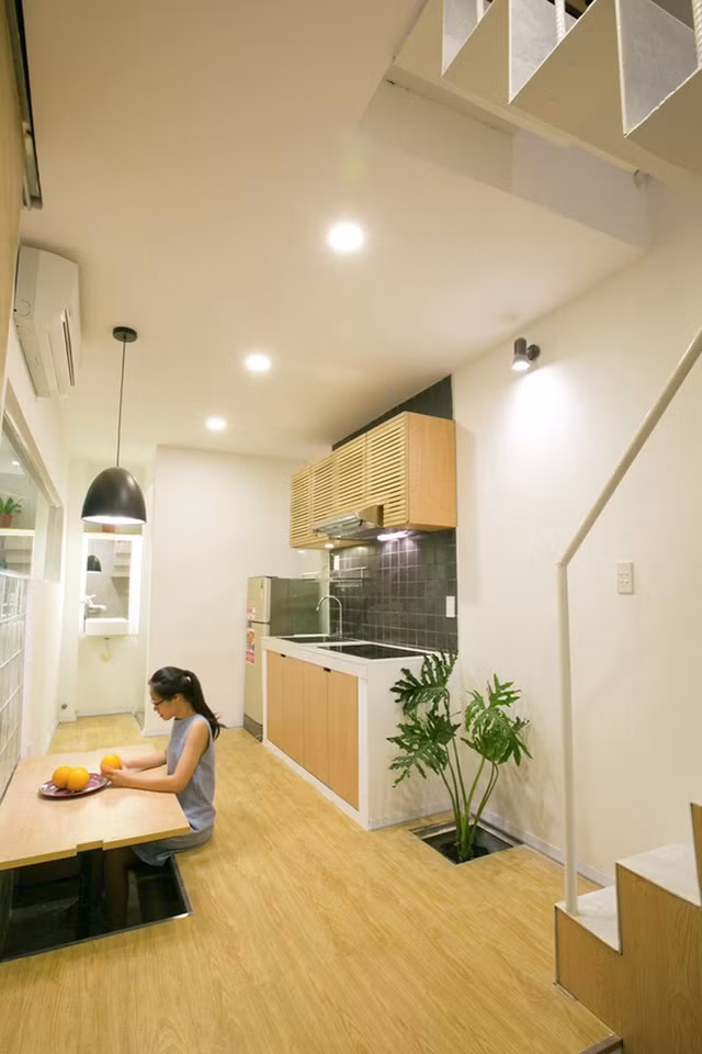 Tầng trệt kết hợp phòng gia đình, phòng ăn tối và nhà bếp. Để làm cho các chức năng này hoạt động linh hoạt và tối đa hóa không gian sử dụng, sàn được nâng lên để lại không gian dưới được phục vụ như băng ghế ăn tối cạnh bàn ăn.