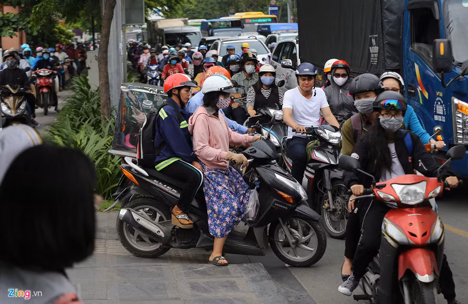 Dưới lòng đường xe cộ chen chúc nhau, nhiều người điều khiến xe máy chạy thành hàng dài trên vỉa hè đường Trường Sơn.