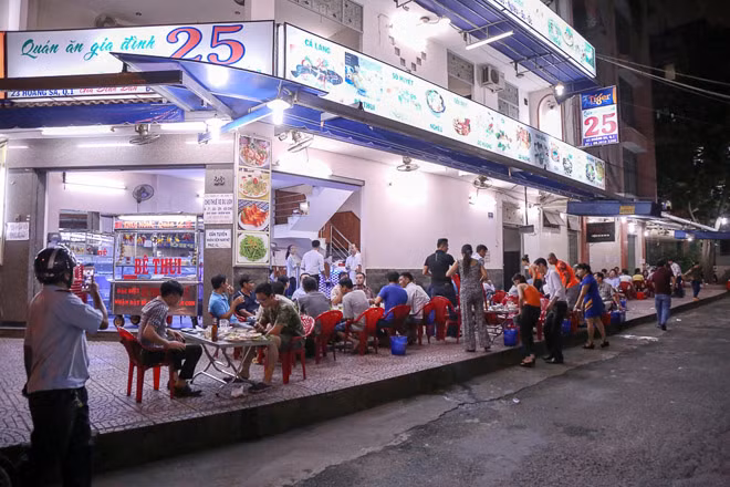 Cách đó không xa, một quán nhậu bày bàn ghế chiếm vỉa hè dài gần 50m cho khách ngồi ăn uống.