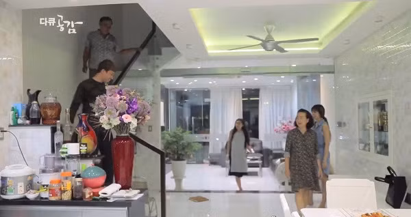 Phòng khách rộng rãi và rất sáng với sơn trắng và đồ nội thất sáng màu. Cửa ra vào chính và lan can cầu thang đều được thiết kế bằng kính trong suốt.