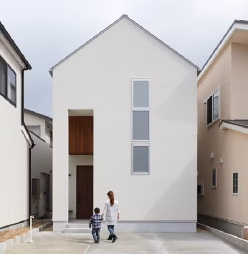 Thiết kế nhà ống kiểu Nhật với mặt tiền kín đáo. Dù sử dụng ba khung cửa sổ nhỏ và một lối vào chật hẹp nhưng ngôi nhà vẫn thoáng máy nhờ giếng trời giữa nhà. Ảnh: ALT Design.