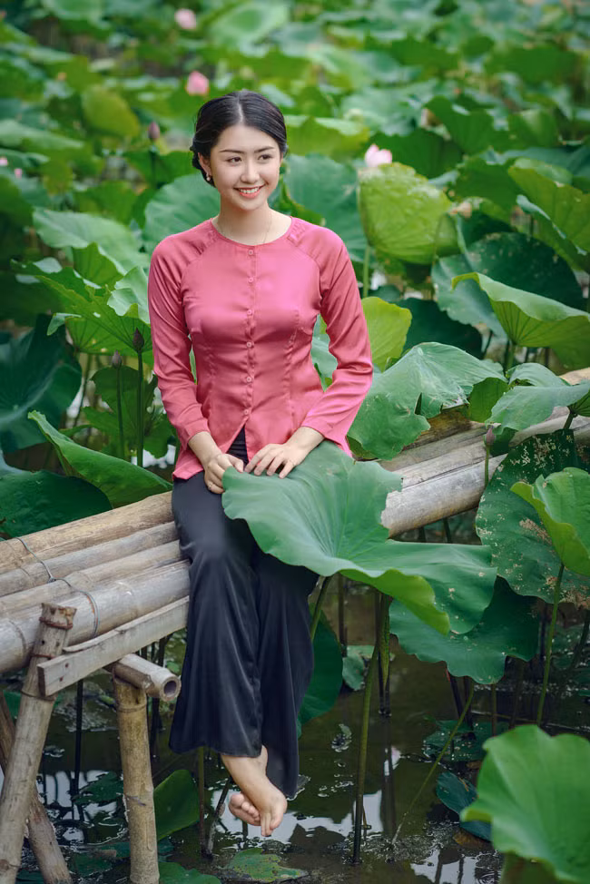 Khác với nhiều thiếu nữ, Ngọc Linh không diện yếm đào "hờ hững" mà lại chọn áo bà ba, hóa thân thành cô thôn nữ, tạo dáng bên sen.