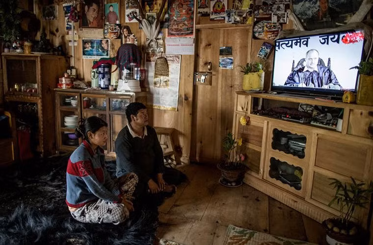 Bác nông dân Kahengpa Apa và con gái đang xem ti vi trong nhà. Internet và ti vi có ở Bhutan vào năm 1999.