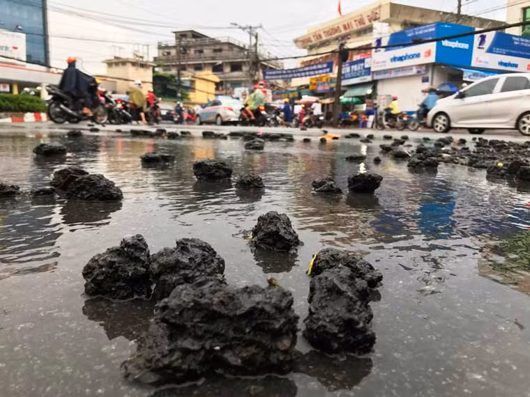 Đất, đá và nhựa đường bị nước mưa cuốn từ dốc cao xuống nằm ngổn ngang ở ngã 5 chợ Thủ Đức.